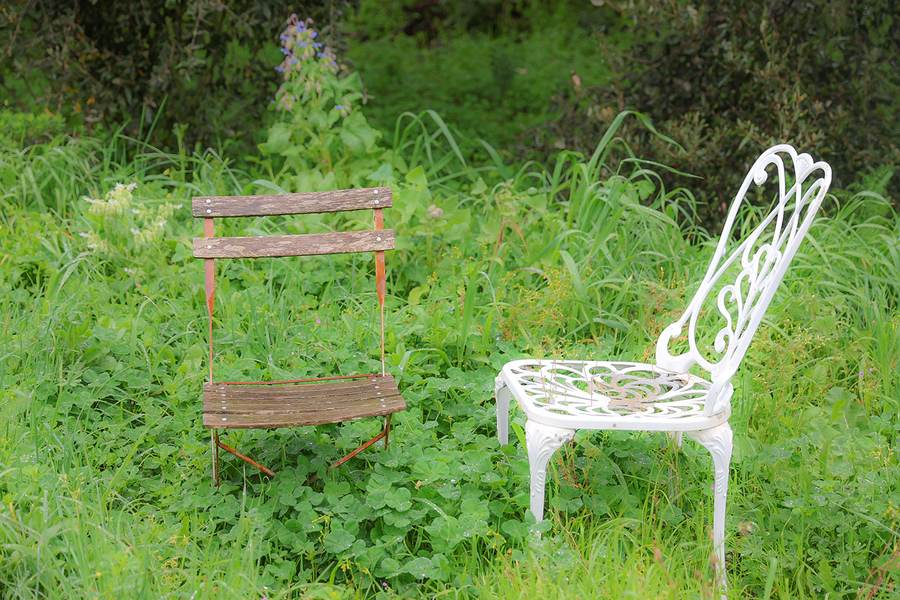 Zwei verschiedene Stühle nebeneinander in einer Wiese