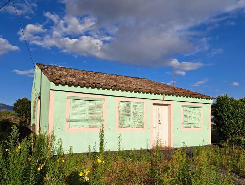 Ein kleines pastellgrünes Haus unter blauem Himmel